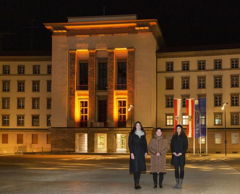 LTPin Sonja Ledl-Rossmann (Mitte), VPin Sophia Kircher (li.) und LRin Eva Pawlata vor dem orange beleuchteten Landhaus, Foto: Tiroler Landtag/Die Fotografen