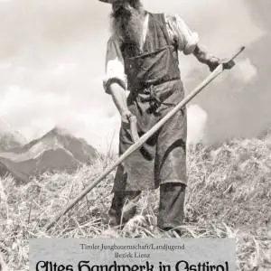 Ein Landwirt mit Bart und Hut beim Mähen mit einer Sense und einem Berg im Hintergrund