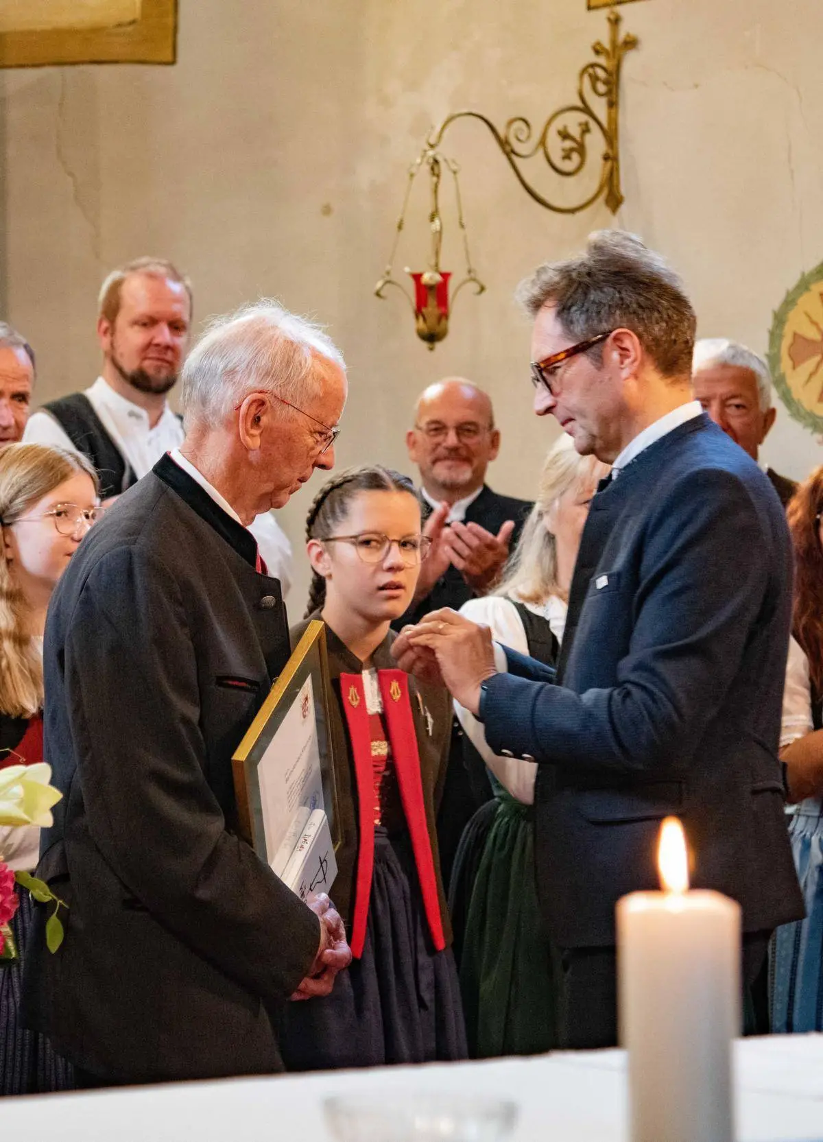 Martin Waldauf (r.) steckt Bartholomäus Klaunzer die Ehrenzeichen des Chorverbandes Tirol und Österreich an.
