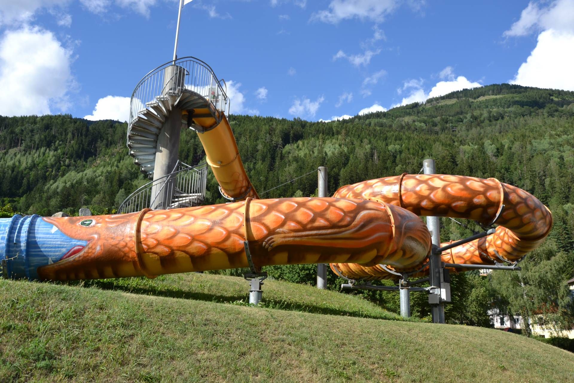 Der heimische K&uuml;nstler Gottfried Recnik verwandelte mit gez&auml;hlten 1.141 Schuppen die Rutsche im Obervellacher Freibad in einen riesigen Lindwurm, inspiriert von der alten Sage des Mallnitzer Lindwurms.