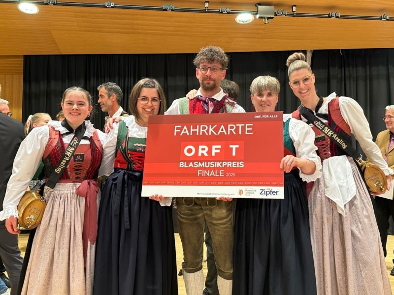 Mitglieder der Musikkapelle Assling in Tracht freuen sich &uuml;ber die Fahrkarte ins Finale des ORF-Blasmusikpreises 2025.